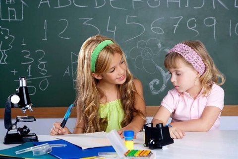 Kids students in classroom helping each other at school desk