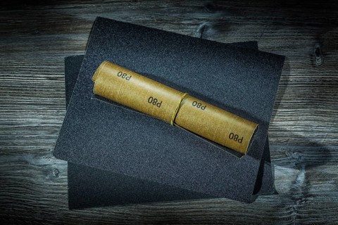 Roll of sandpaper and sheets of it on vintage wood