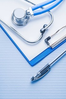 Ballpoint pen and stetoscope with clipboard on blue background medical concept