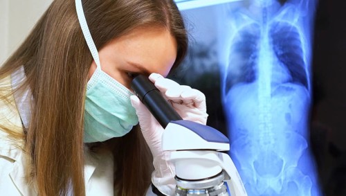 Scientist in medical mask in laboratory. Chest x-ray film on background