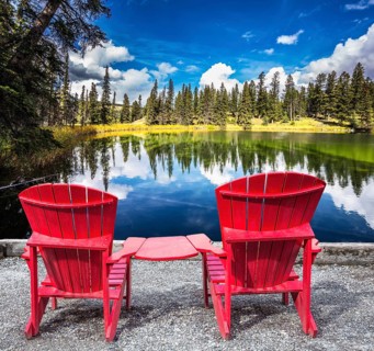 Jasper National Park in the Rocky Mountains. Two red plastic chairs on the lake. On shores of the