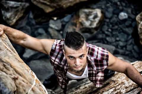 Three Quarter Shot of an Attractive Athletic Young Man Climbing a Rock at the River or by the Sea