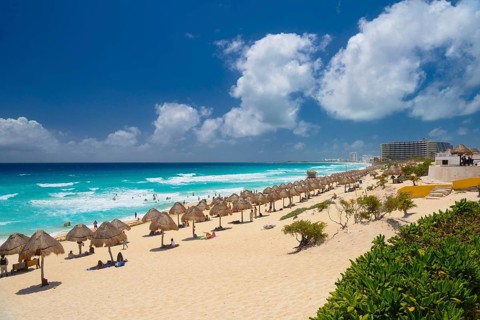 Umbrellas on a sandy beach with azure blue water on a sunny day near Cancun, Mexico, Central