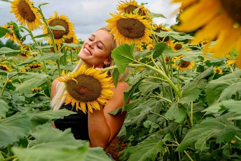 A stunning blonde model gracefully poses in a vibrant sunflower field, basking in the warmth of a