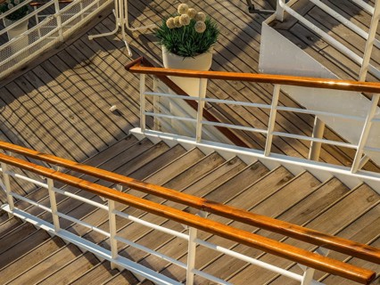 Wooden staircase with railing on a ship deck and a decorative potted plant with flowers, stockholm,