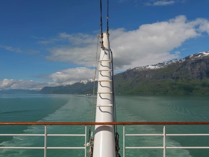 View from a boat access area over green water and surrounded by mountains and clouds, sailing in a