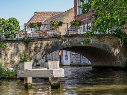 Picturesque stone bridge with flower boxes in bloom over a quiet canal, Bruges, Flanders, Belgium,