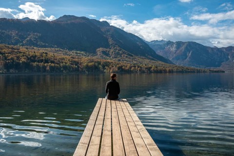 Sitting on a small jetty and enjoying the view on the landscape of lake Bohinj in the Triglav