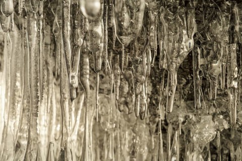 Ice cave on Baikal lake in winter. Clear transparent ice and icicles in grotto. Olkhon island,