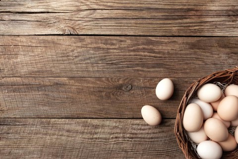 Organic chicken eggs in basket on wooden background. Organic household concept with eggs from
