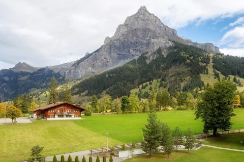 Wooden chalet in Kandersteg village, Canton Bern, Switzerland, Europe, Autumn trees and mountains