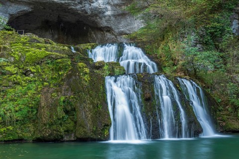 Waterfall from the source of the Lison in a haven of peace with its waterfall surrounded by forest.