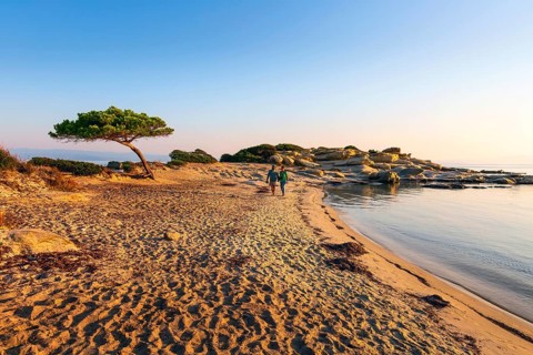 Vourvourou, Sithonia, Greece, September 17, 2019: Couple walking at sunrise Karidi beach.