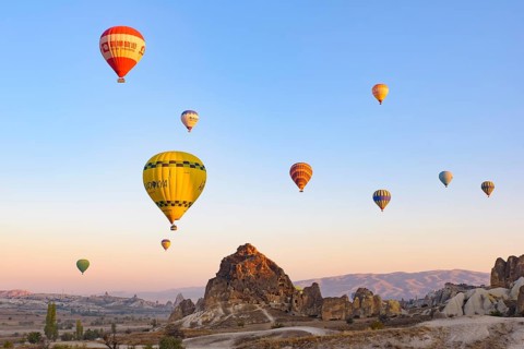 Flying hot air balloons and rock landscape at sunrise time in Goreme, Cappadocia, Turkey, Asia