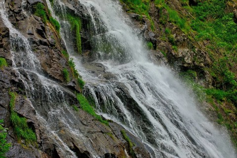 Close-up of a waterfall flowing over moss-covered rocks and conveying freshness, waterfall,