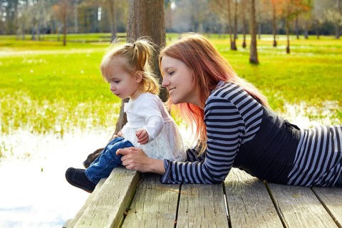 Daughter and mother playing together in the park lake pier