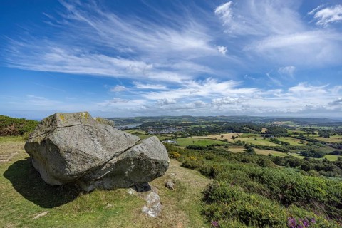 Large rock on a hill with sweeping views over a green landscape around Conwy and Conwy Castle on
