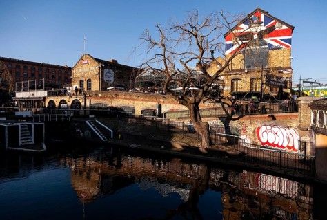 A beautiful canal scene with a building adorned with a British flag, a leafless tree, and