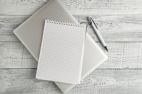 White paper Notepad and laptop on vintage shabby white wooden background. the view from the top.