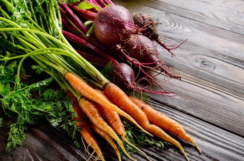 Fresh organic beetroots and carrots on kitchen wooden rustic table close up view