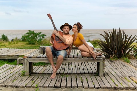 Couple of musicians sitting on the beach looking at the camera