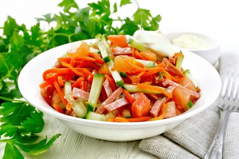 Salad from smoked sausage, spicy carrot, tomato, cucumber and spices with mayonnaise, kitchen