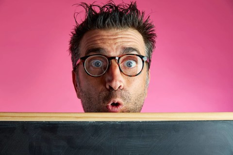 Nerd man crazy behind a blackboard funny surprise gesture in pink background