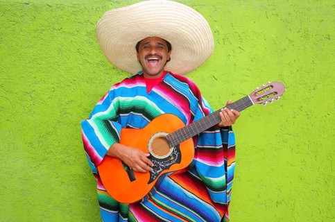 Mexican typical man playing guitar poncho on green wall