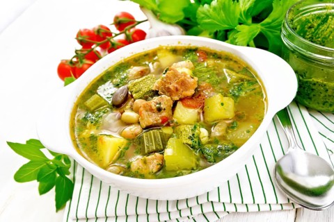 Soup with pisto sauce, pork fat, tomatoes, zucchini, beans, celery and leek in a bowl on a towel on