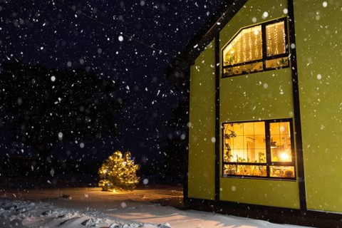 Cozy festive window of the house outside with the warm light of fairy lights garlands inside,