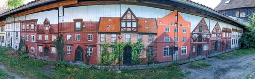 Panoramic photo of garage doors, with graffiti facades of buildings from the medieval old town of
