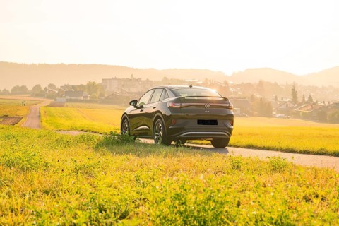 SUV driving on a country road with a view of a town at sunset, VW ID5 electric car, Calw, Black