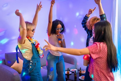 Group of diverse friends enjoying karaoke night, singing and dancing together in a colorful,