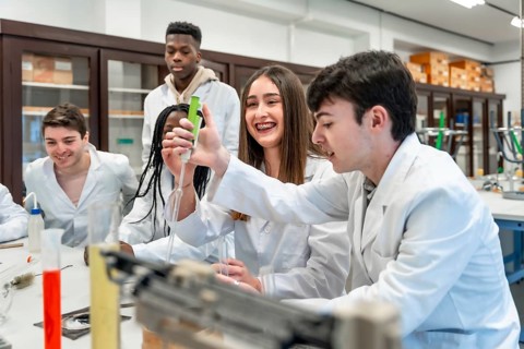 Diverse group of university chemistry students conducting an experiment in a lab, using lab coats