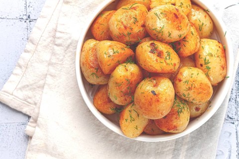 Baked new potatoes, with butter and dill, on a white plate, at home, no people