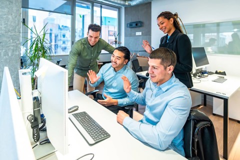 Business colleagues waving enthusiastically at the computer during an engaging video call in a