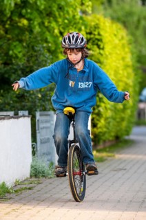Boy practising to ride a unicycle, sidewalk, Germany