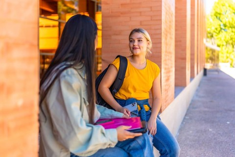 Multi-ethnic female chinese and caucasian friends sitting and talking at the university campus