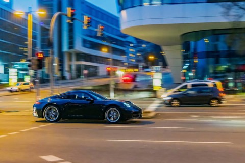 Porsche at night in front of urban surroundings with modern architecture, pull-along. Stuttgart,