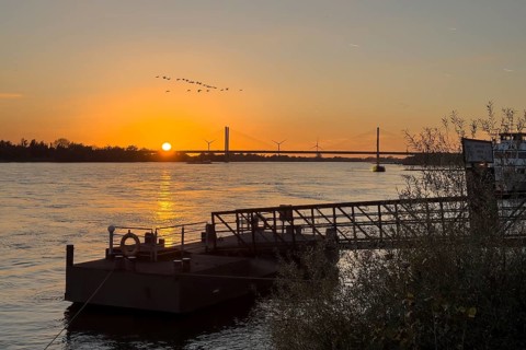 Sunset over the river Rhine Lower Rhine, in the foreground jetty with bridge to the shore, in the