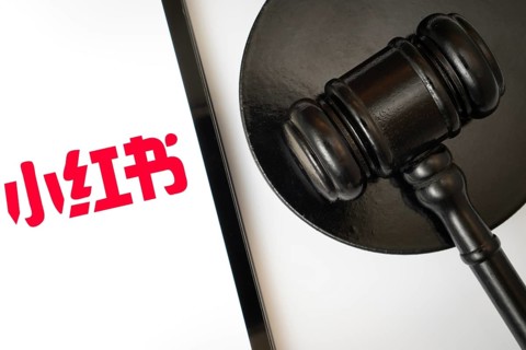 An iPad displays the RedNote (Xiaohongshu) logo alongside a judge's gavel