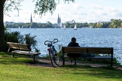 Leisure activities in summer, bicycle and woman on park bench, behind them sailing boats in front