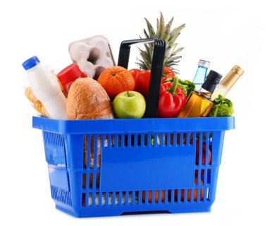 Plastic shopping basket with assorted grocery products isolated on white