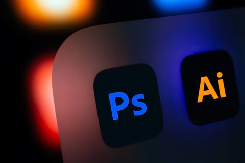 A close up of an iPad screen displaying the Adobe photoshop and adobe illustrator app