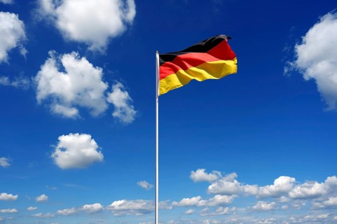 Flag of Germany fluttering in the blue sky with cumulus clouds