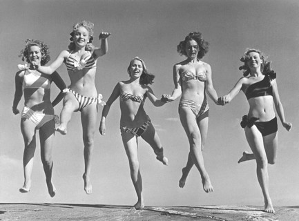 1940s summer. A group of young women in their bikinis are happy on this summer's day, jumping of
