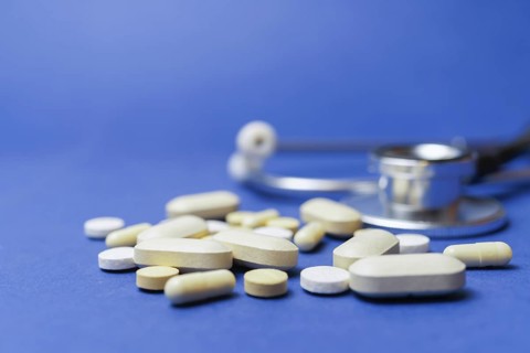 Stethoscope with pills on a blue background with a large space for text