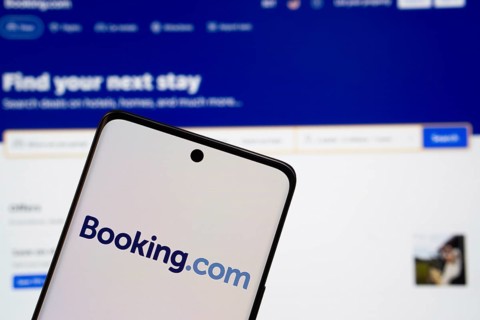 Booking.com logo is displayed on a smartphone screen, with the booking.com website visible on a