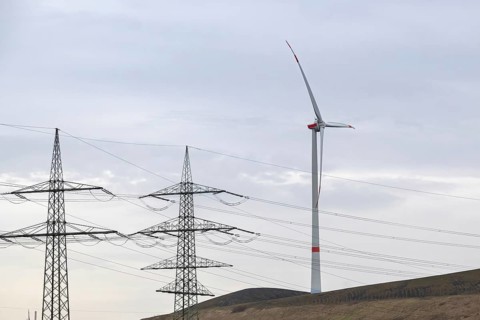 High-voltage pylons with wind turbine in german industrial landscape