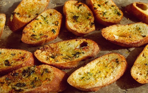 Baguette toasts, baked in the oven, with garlic butter and herbs, homemade, on a platter, top view